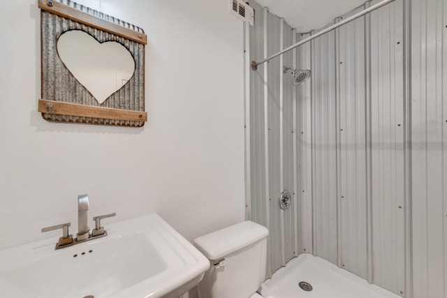 bathroom featuring a shower stall, toilet, a sink, and visible vents