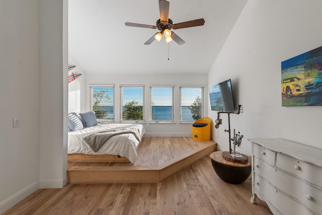 bedroom with light wood finished floors, vaulted ceiling, baseboards, and ceiling fan