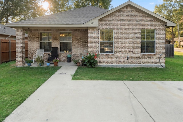 ranch-style home featuring brick siding, a front lawn, and fence