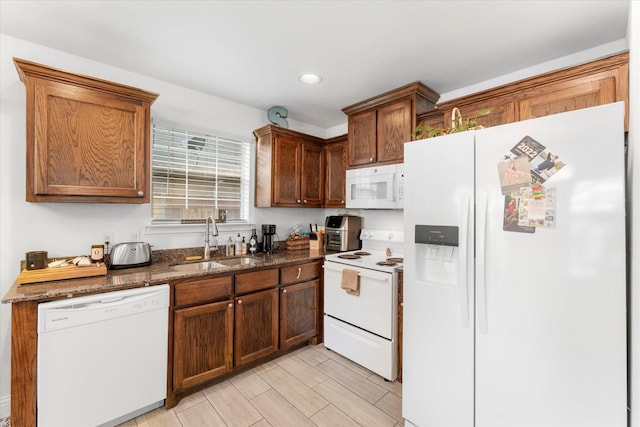 kitchen featuring white appliances, a sink, and dark stone countertops