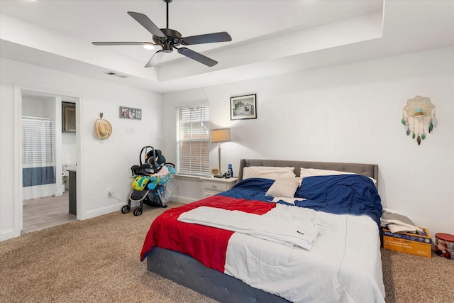 bedroom with connected bathroom, carpet floors, a raised ceiling, baseboards, and visible vents