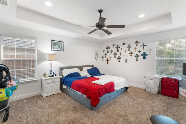 bedroom featuring light colored carpet, baseboards, a tray ceiling, and visible vents