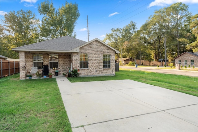 view of front of home featuring fence, a shingled roof, a front lawn, and brick siding