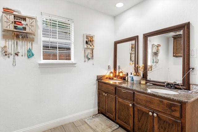 full bathroom with baseboards, a sink, and double vanity