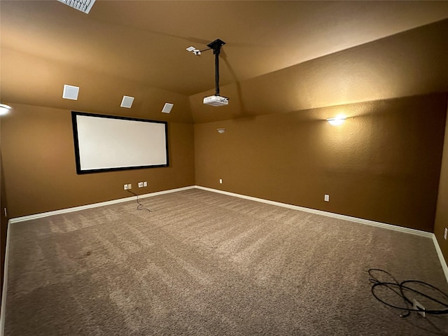 carpeted home theater room featuring vaulted ceiling and baseboards
