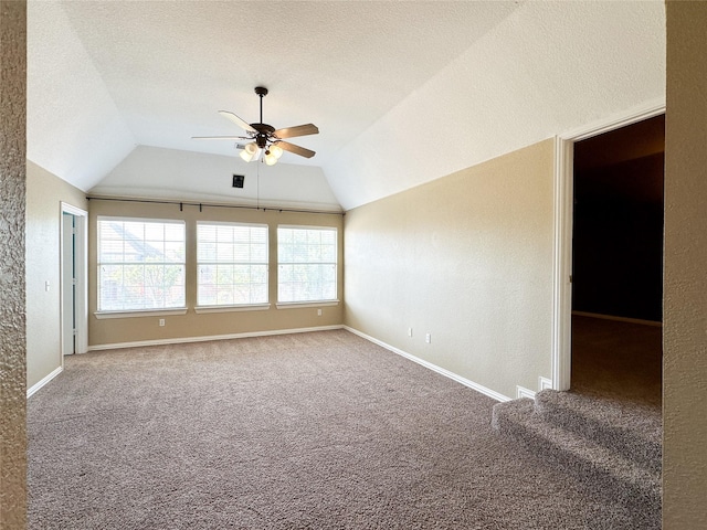 carpeted empty room featuring lofted ceiling, a textured ceiling, baseboards, and ceiling fan