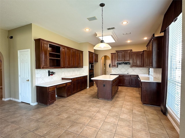 kitchen with visible vents, arched walkways, black oven, and a kitchen island