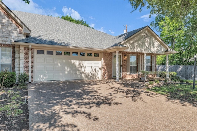 view of front facade featuring brick siding, driveway, a garage, and roof with shingles