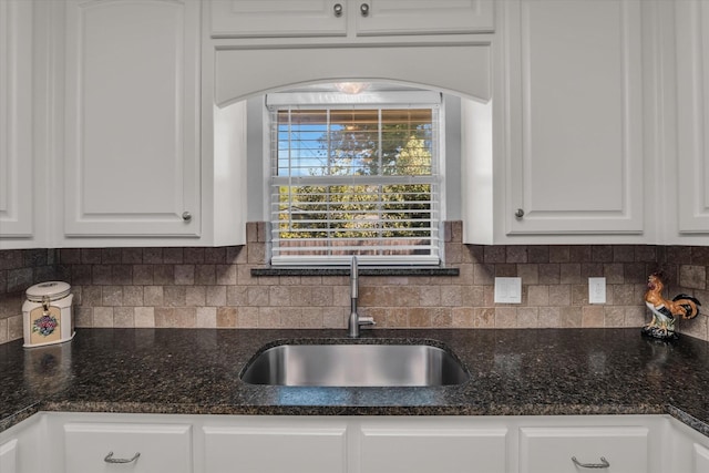 kitchen with white cabinets, arched walkways, a sink, and backsplash