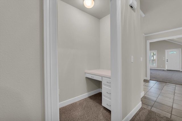 walk in closet with carpet flooring, tile patterned flooring, and built in study area