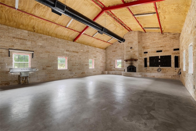 unfurnished living room featuring high vaulted ceiling and concrete floors
