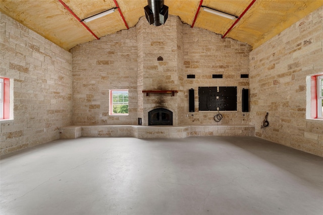 unfurnished living room featuring vaulted ceiling, concrete flooring, and a fireplace