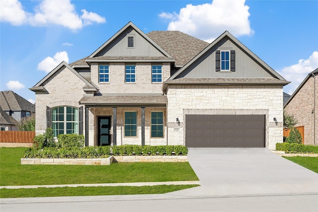 view of front facade with a shingled roof, a front lawn, concrete driveway, and fence