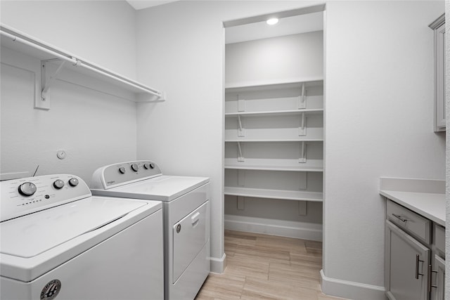 clothes washing area with light wood-style floors, baseboards, washer and dryer, and laundry area