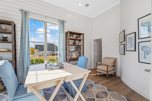 office area featuring baseboards, wood walls, wood finished floors, a high ceiling, and ornamental molding