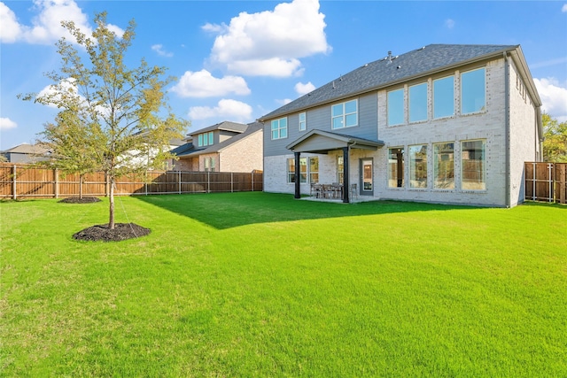 rear view of house featuring a fenced backyard, brick siding, a patio, and a lawn