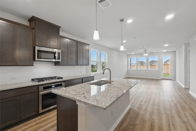 817 Hadley Dr, Princeton, TX 75071 - kitchen with appliances with stainless steel finishes, decorative backsplash, light wood-style flooring, dark brown cabinetry, and hanging light fixtures