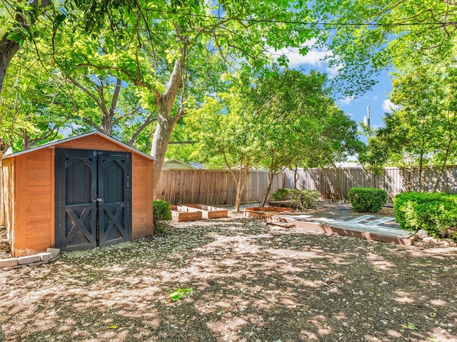 fenced backyard featuring a storage shed, an outbuilding, and a garden