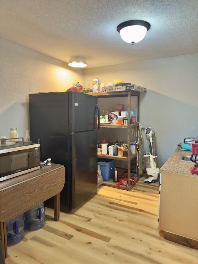 157 Business Blvd, Granbury, TX 76049 - kitchen with freestanding refrigerator, light wood-type flooring, stainless steel microwave, and a textured ceiling