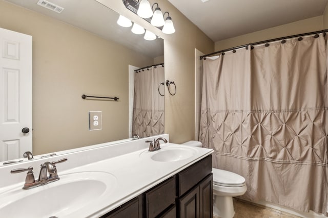 bathroom with double vanity, visible vents, toilet, and a sink