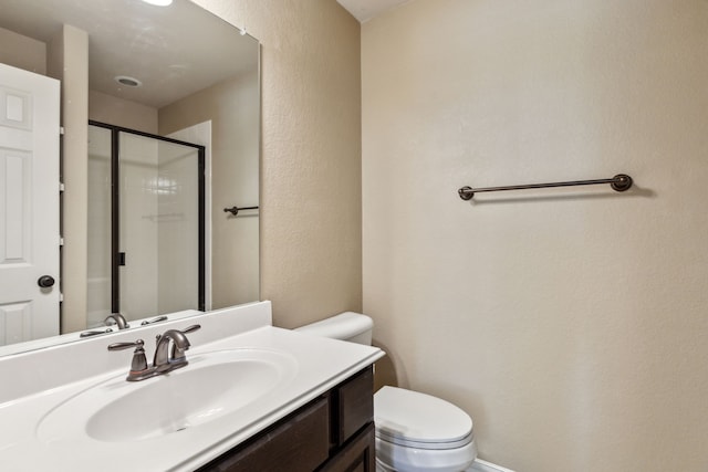 bathroom with a stall shower, a textured wall, vanity, and toilet