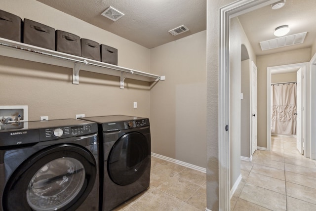 laundry room with washing machine and clothes dryer, visible vents, and light tile patterned floors