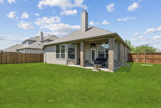 rear view of property with a fenced backyard, a chimney, a patio area, and a lawn