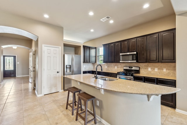 kitchen featuring a sink, decorative backsplash, a breakfast bar, appliances with stainless steel finishes, and visible vents