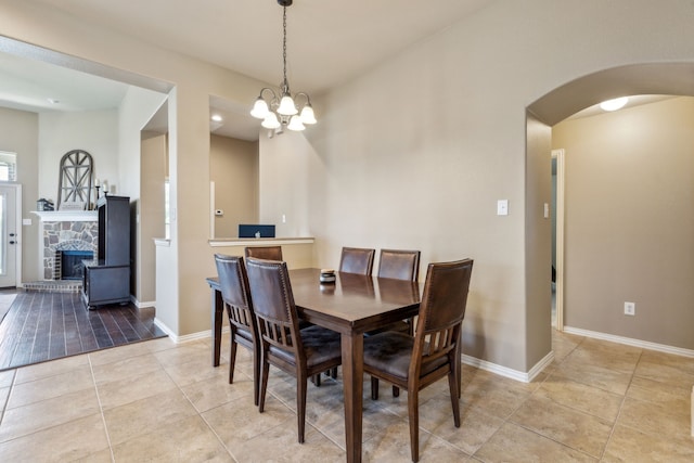 dining space featuring arched walkways, an inviting chandelier, baseboards, and light tile patterned floors