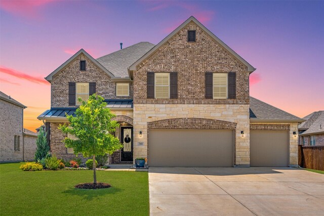 traditional home with roof with shingles, a front lawn, a standing seam roof, driveway, and brick siding