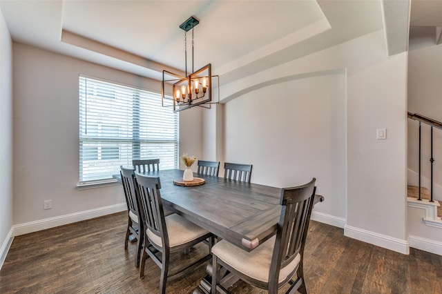 dining room featuring a chandelier, baseboards, wood finished floors, and a tray ceiling