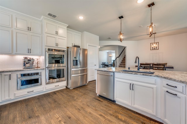 kitchen featuring white cabinets, stainless steel appliances, arched walkways, a sink, and visible vents