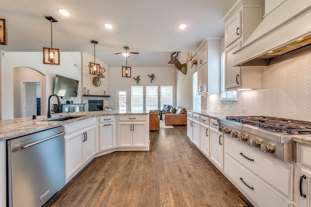 kitchen featuring a sink, open floor plan, a ceiling fan, appliances with stainless steel finishes, and premium range hood