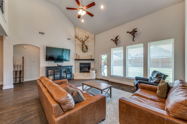 living area with high vaulted ceiling, a stone fireplace, ceiling fan, arched walkways, and visible vents