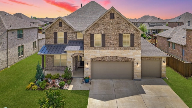 view of front of house with a standing seam roof, brick siding, a front yard, and concrete driveway