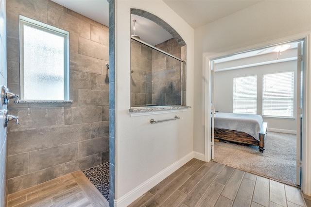 bathroom featuring ensuite bath, baseboards, walk in shower, and wood finished floors