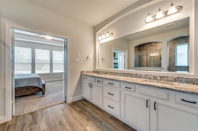 bathroom featuring a sink, double vanity, a stall shower, visible vents, and wood finished floors