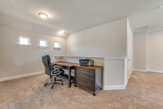 carpeted office space featuring baseboards, vaulted ceiling, and visible vents