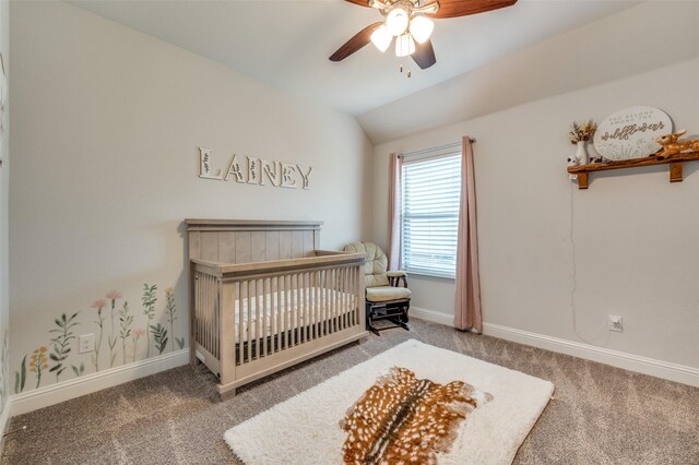carpeted bedroom with lofted ceiling, a crib, a ceiling fan, and baseboards