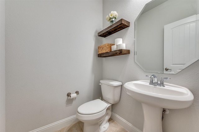 half bath featuring tile patterned floors, baseboards, a sink, and toilet