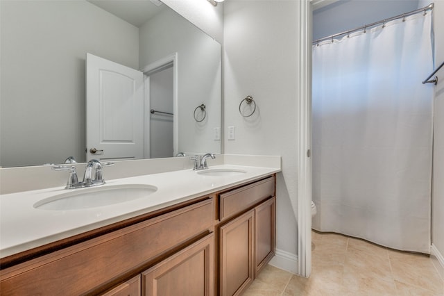 bathroom featuring baseboards, a sink, and double vanity