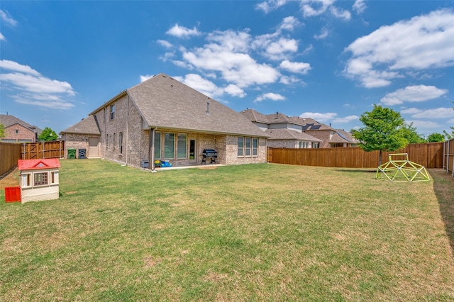 back of property featuring a fenced backyard, brick siding, a patio area, a shingled roof, and a yard
