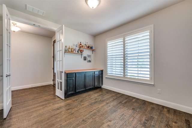 bar with baseboards, visible vents, dark wood-type flooring, and a bar