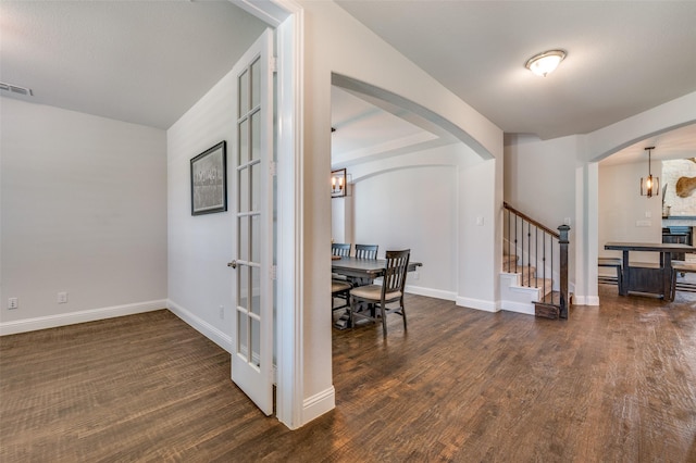 foyer with a chandelier, arched walkways, wood finished floors, and stairs