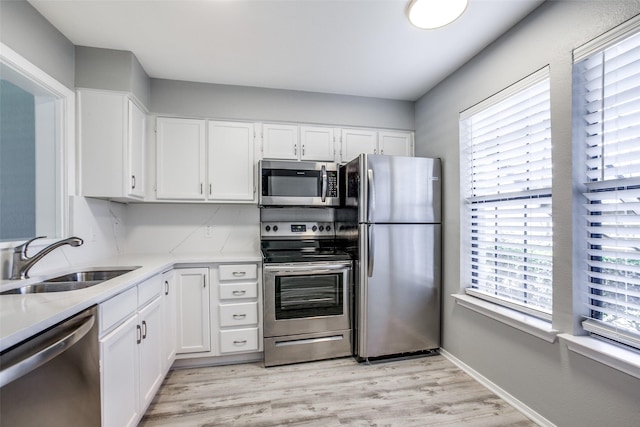 kitchen with plenty of natural light, white cabinets, stainless steel appliances, and a sink