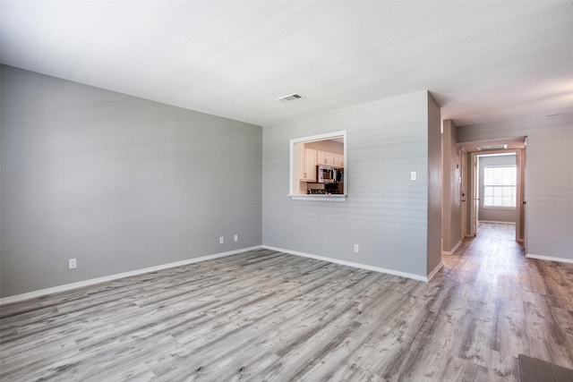 spare room featuring baseboards, wood finished floors, and visible vents