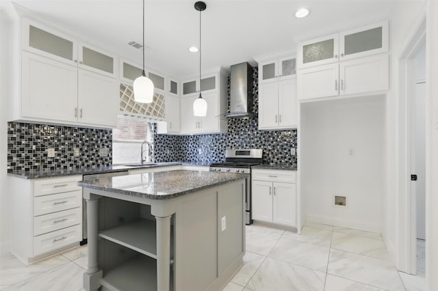 kitchen with wall chimney exhaust hood, white cabinets, a center island, dark stone countertops, and gas stove