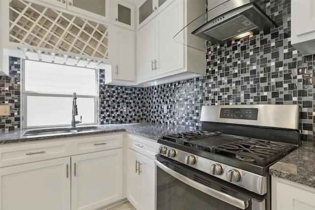 kitchen featuring stainless steel range with gas cooktop, tasteful backsplash, a sink, white cabinetry, and under cabinet range hood
