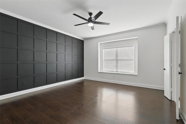 spare room with wood finished floors, baseboards, ornamental molding, and a decorative wall
