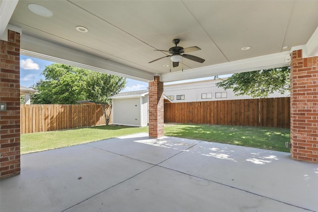 view of patio with a fenced backyard, an outdoor structure, a ceiling fan, and a shed